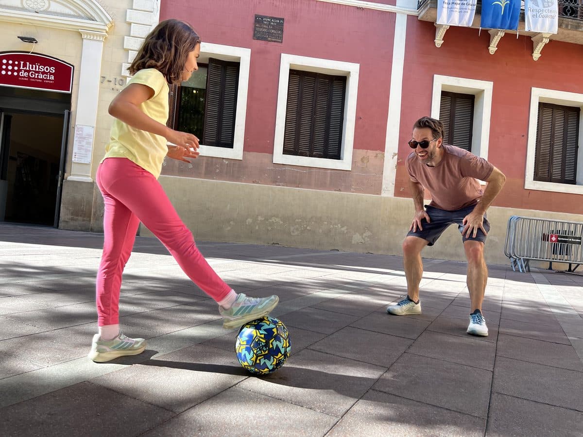 A child and an adult playing football in a Barcelona plaça