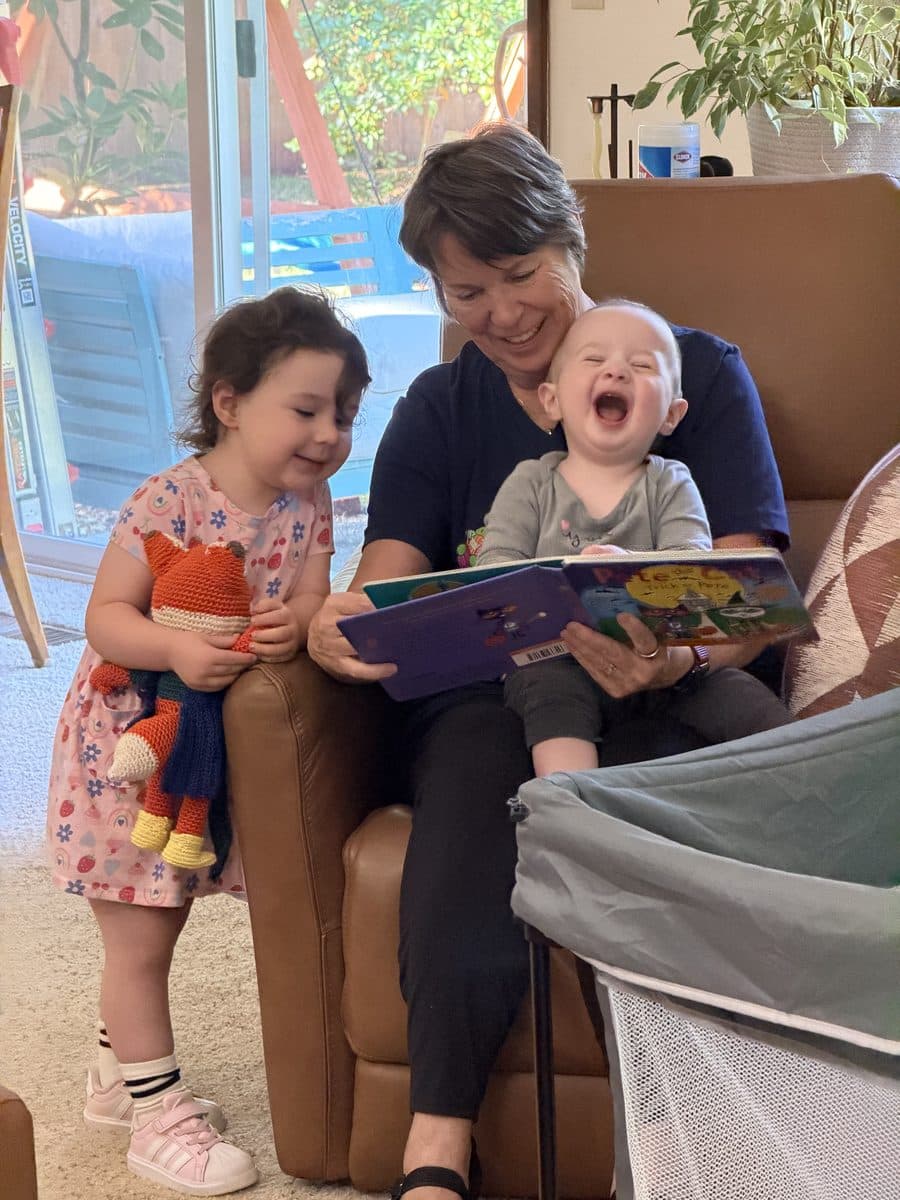 A grandmother reading a picture book to two small grandchildren